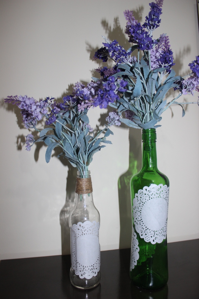 Garrafa de vinho,  papel rendado e flores artificiais